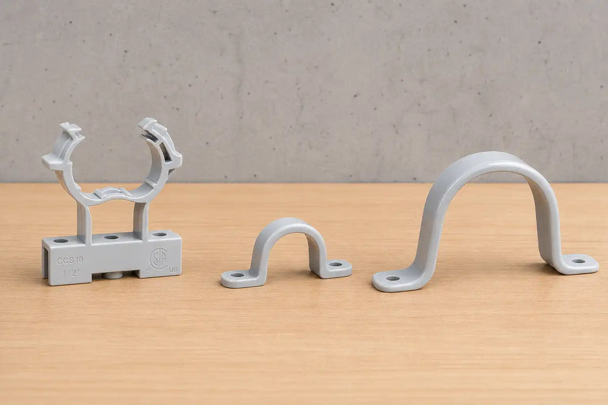 Supports en plastique gris pour canaux électriques, présentés sur un plancher en bois.